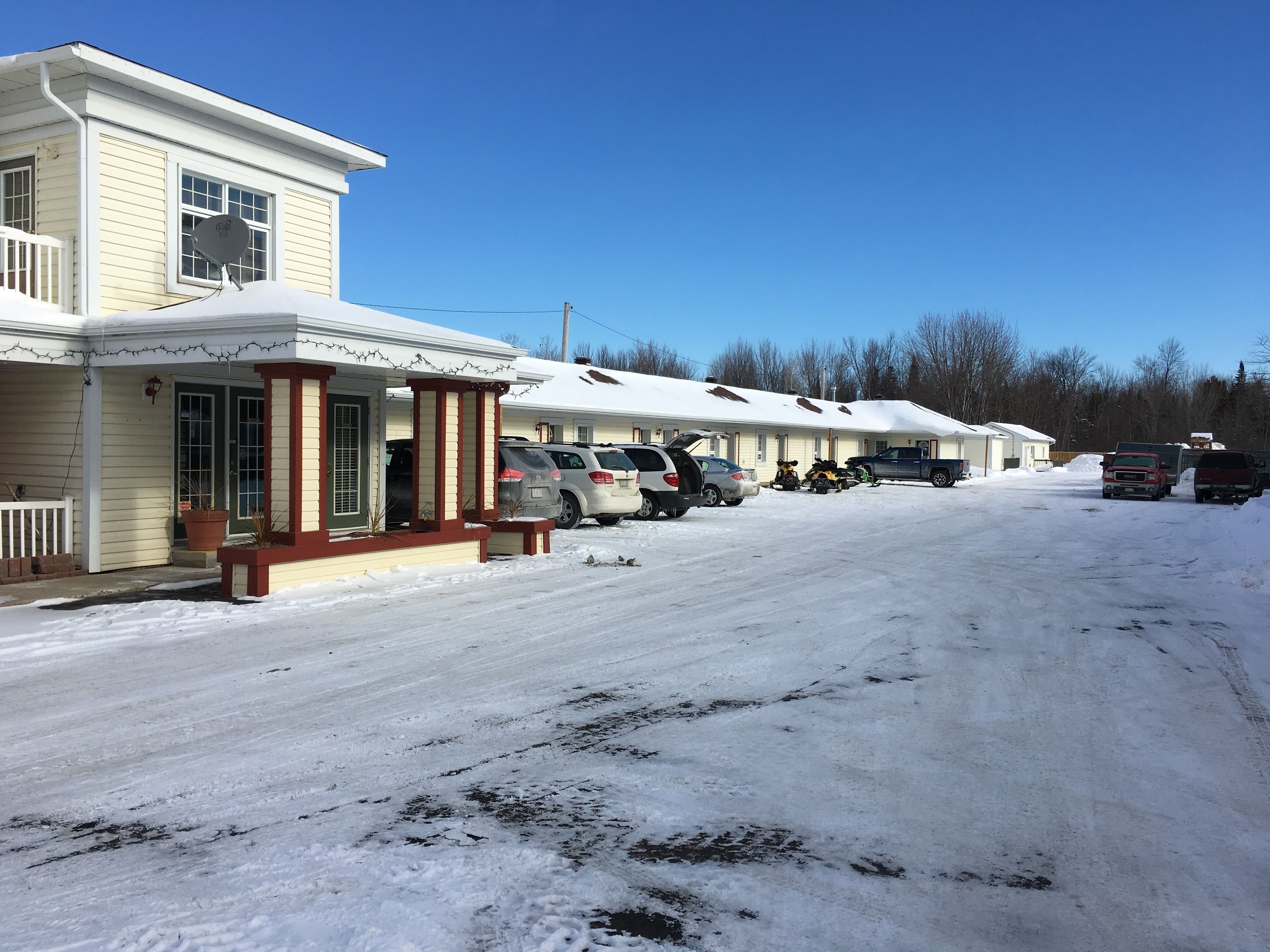 A row of motel buildings with parking spaces in front.