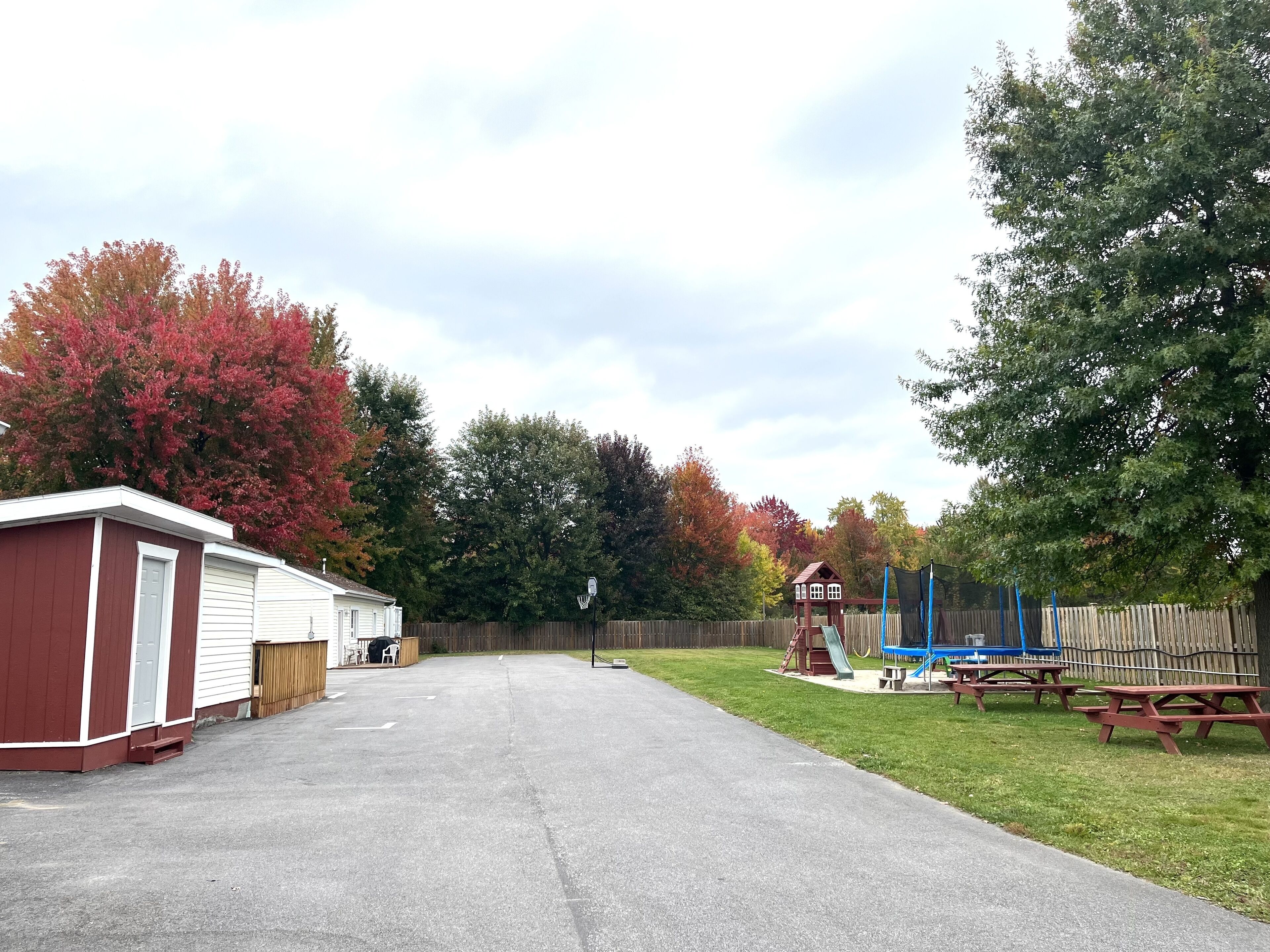 Un quartier résidentiel doté d’un garage, d’un panier de basketball, d’une aire de jeux avec un toboggan et de tables de pique-nique.