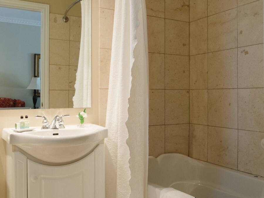 A bathroom with a sink, mirror, and bathtub.