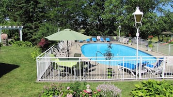 Una piscina al aire libre de temporada, sombrillas, tumbonas