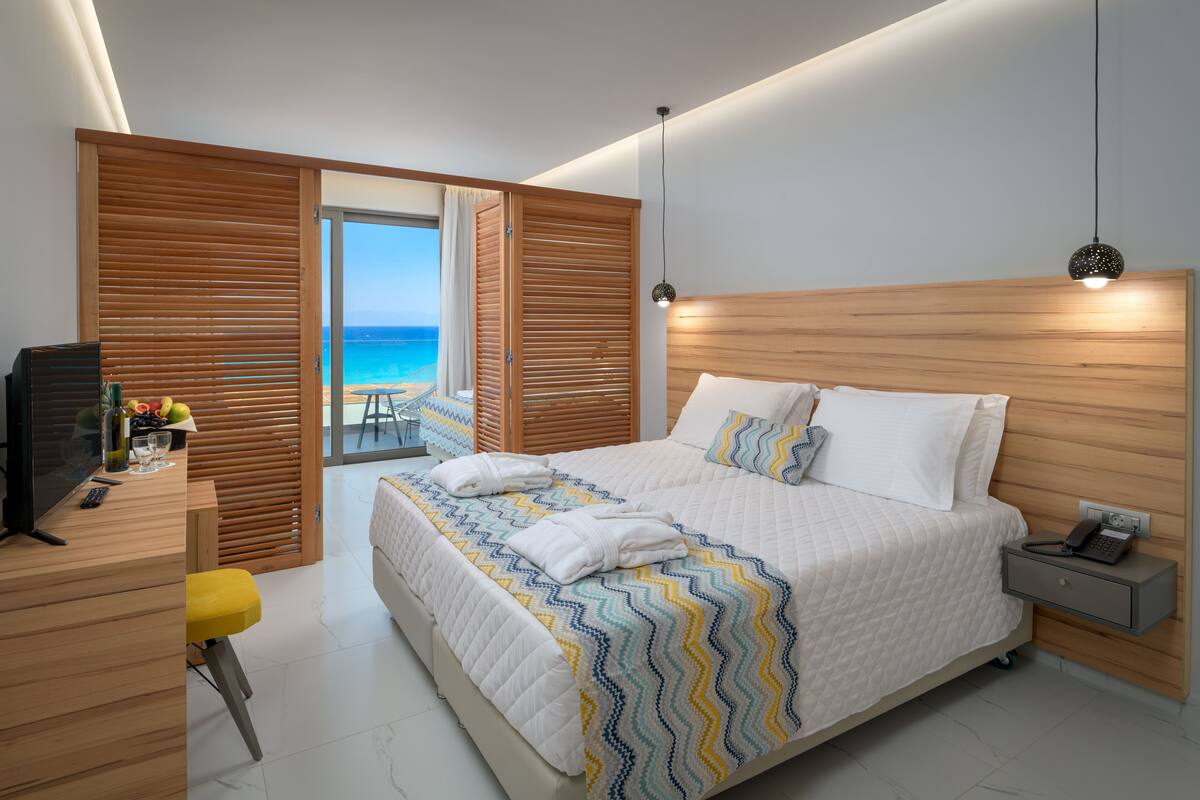 Une chambre moderne avec un grand lit, une tête de lit en bois et une vue sur la plage.