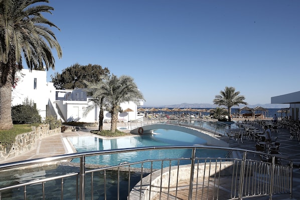 Una piscina al aire libre, sombrillas, sillones reclinables de piscina