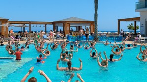 Una piscina amb gent a l'aigua, envoltada de gandules i paraigües.