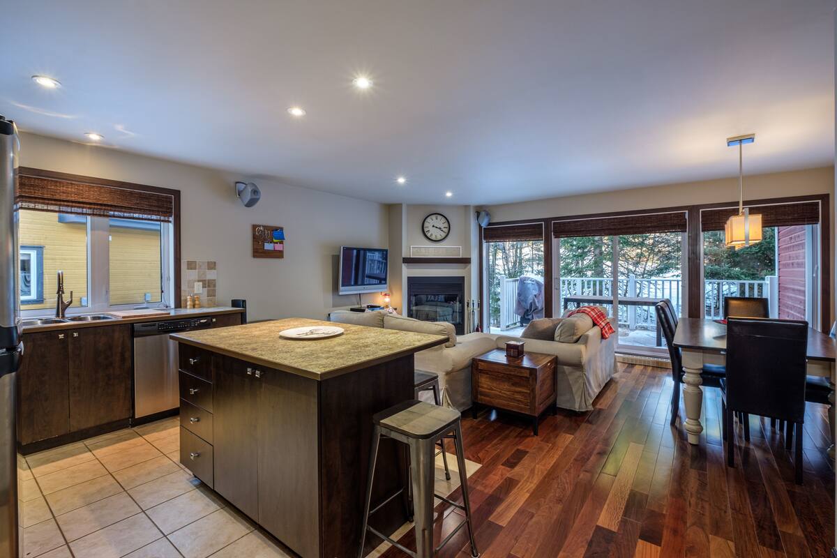 A modern kitchen with a central island, a dining area with a table and chairs, and a cozy seating area with a sofa and a coffee table.