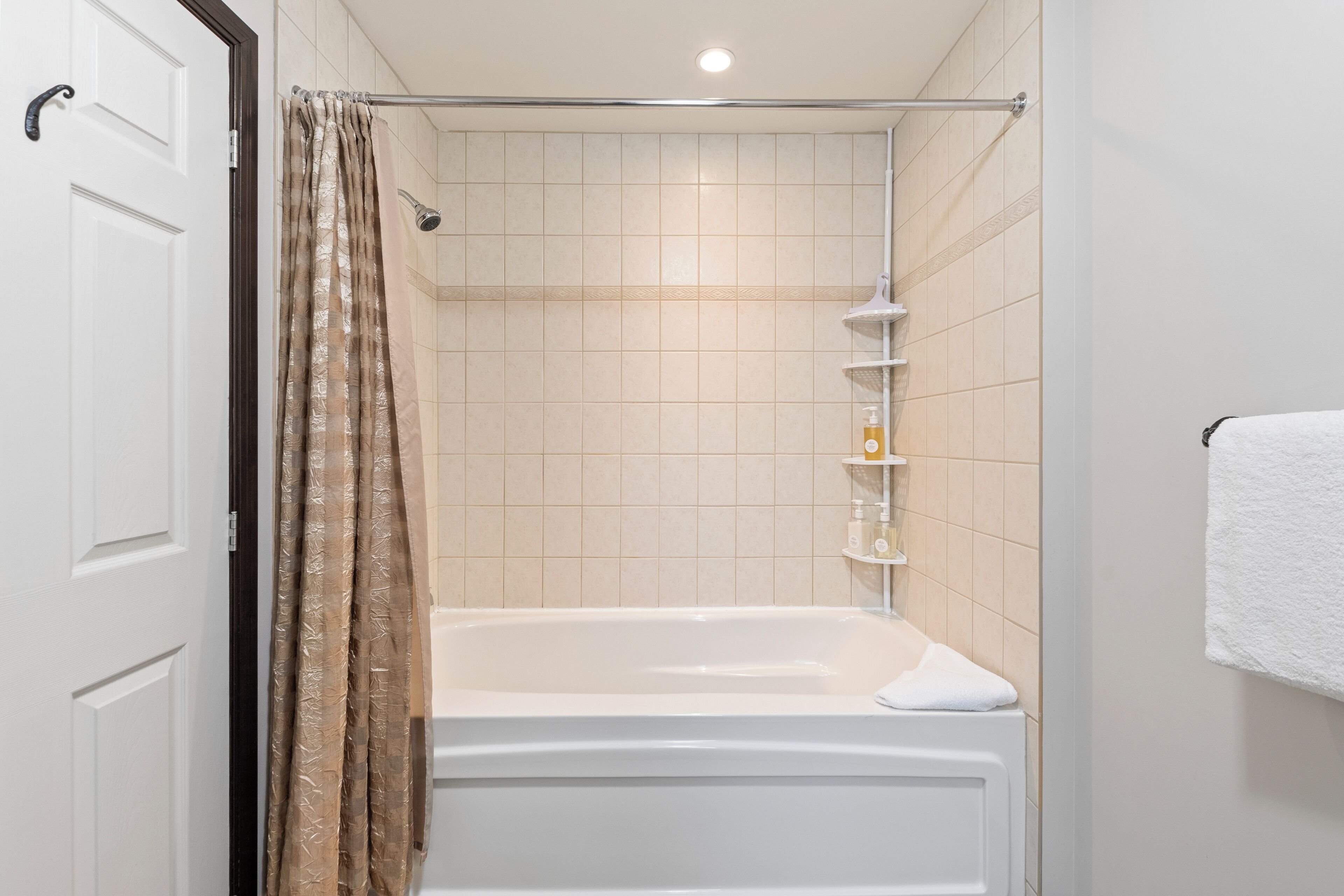 A bathroom with a bathtub, a shower curtain, and a towel rack.