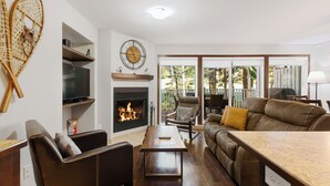 Una sala de estar con chimenea, muebles de cuero y televisor.