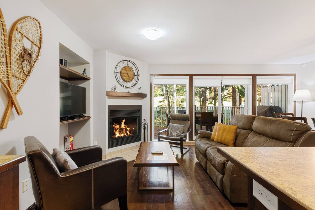 A living room with a fireplace, leather furniture, and a television.