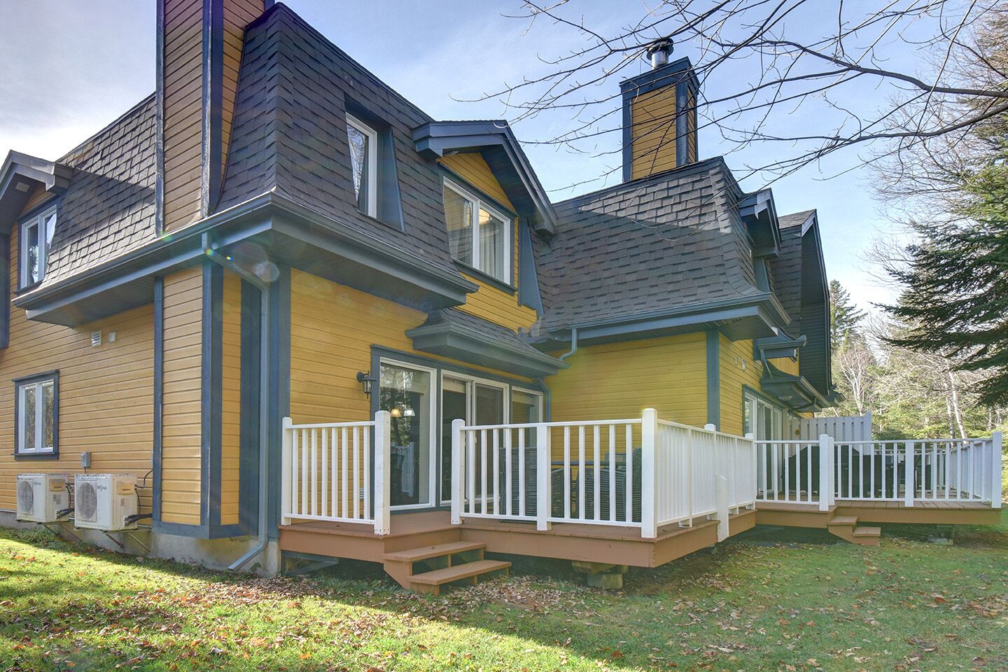 A two-story house with a front porch, a chimney, and a deck.