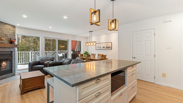 Una cocina moderna con una isla grande, armarios de madera e iluminación colgante.