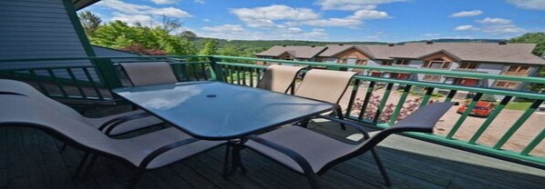 A balcony with a table and chairs, overlooking a row of houses and a clear sky. - La Clairiere - RVMT (Mont-Tremblant)