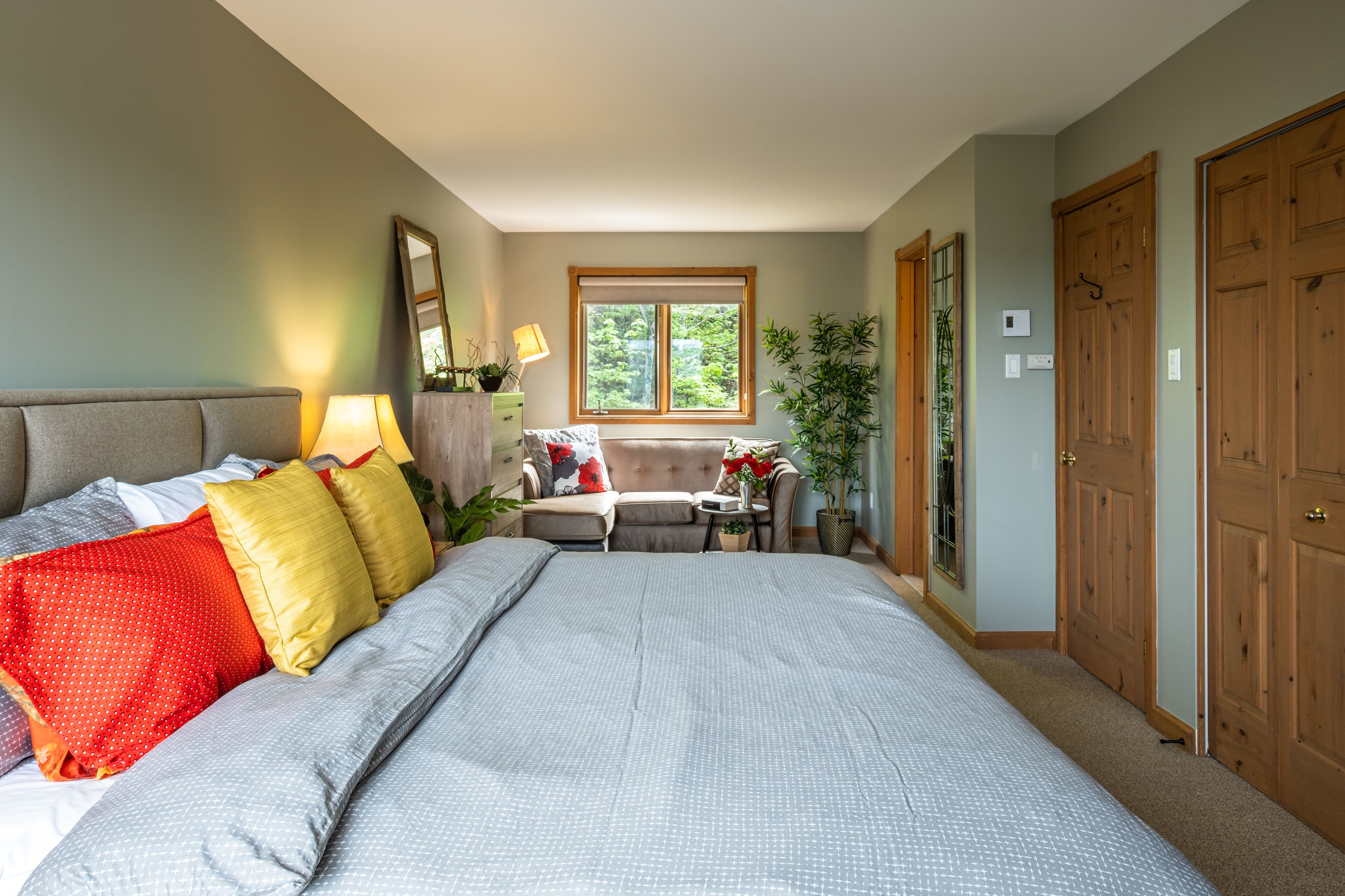 Ein Schlafzimmer mit einem großen Bett, einem Nachttisch, einer Kommode, einem Fenster und einer Tür.