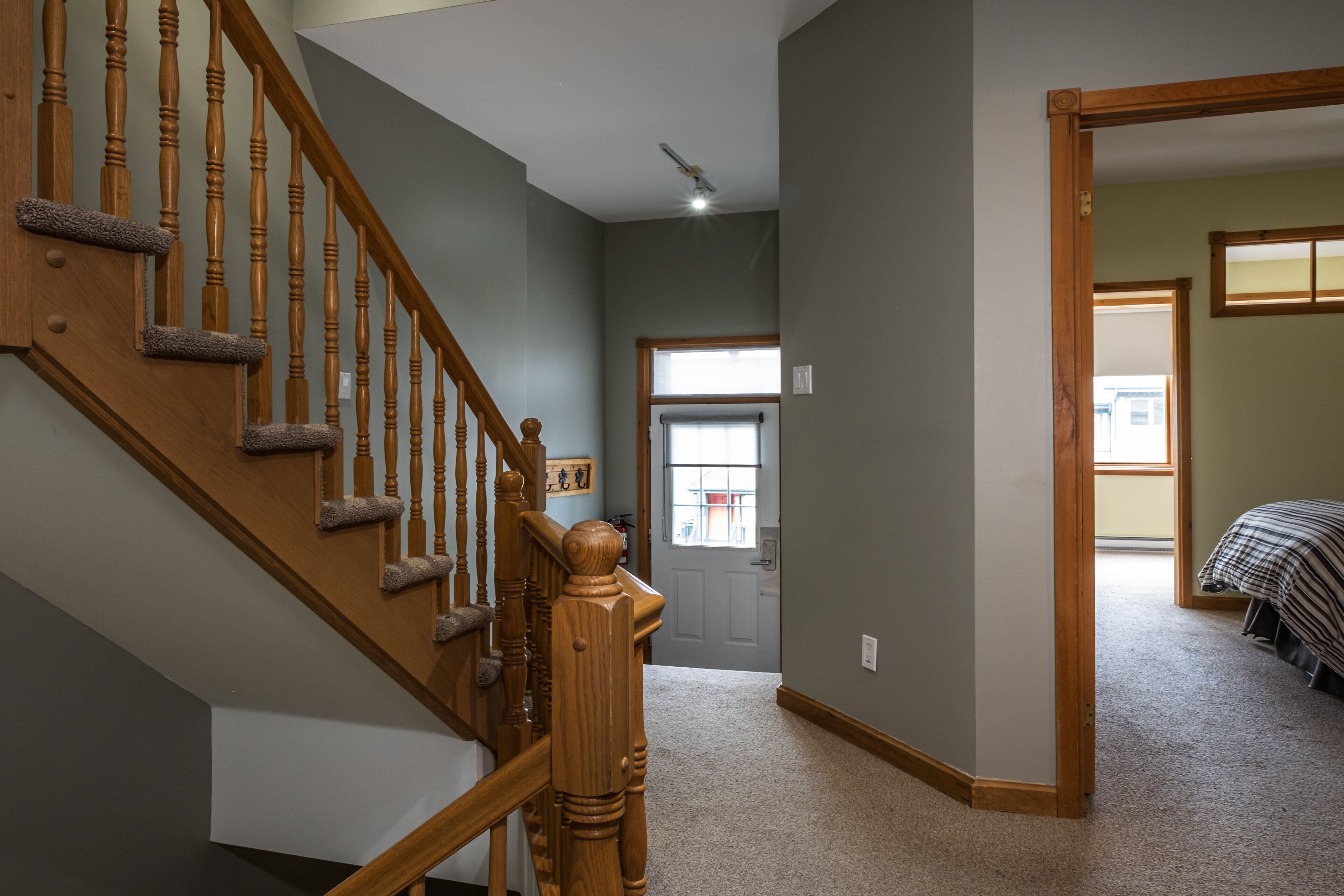 A staircase with wooden balusters and carpeted steps leading to a door with a window.