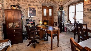A stone-walled room with a wooden desk, chairs, and a fireplace. - Arxontiko Kefalari (Sikyona)