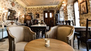 A dining area with stone walls, wooden furniture, and ornate ceiling decorations. - Arxontiko Kefalari (Sikyona)