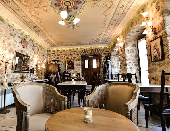 A dining area with stone walls, wooden furniture, and ornate ceiling decorations.