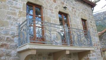 Un bâtiment en pierre doté d’un balcon orné de balustrades en fer forgé et de fenêtres à cadre en bois.