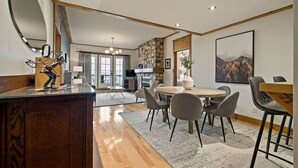 A modern kitchen with a wooden countertop, a large mirror, and a dining area with a round table and chairs. - L'Equinoxe – RVMT (Mont-Tremblant)