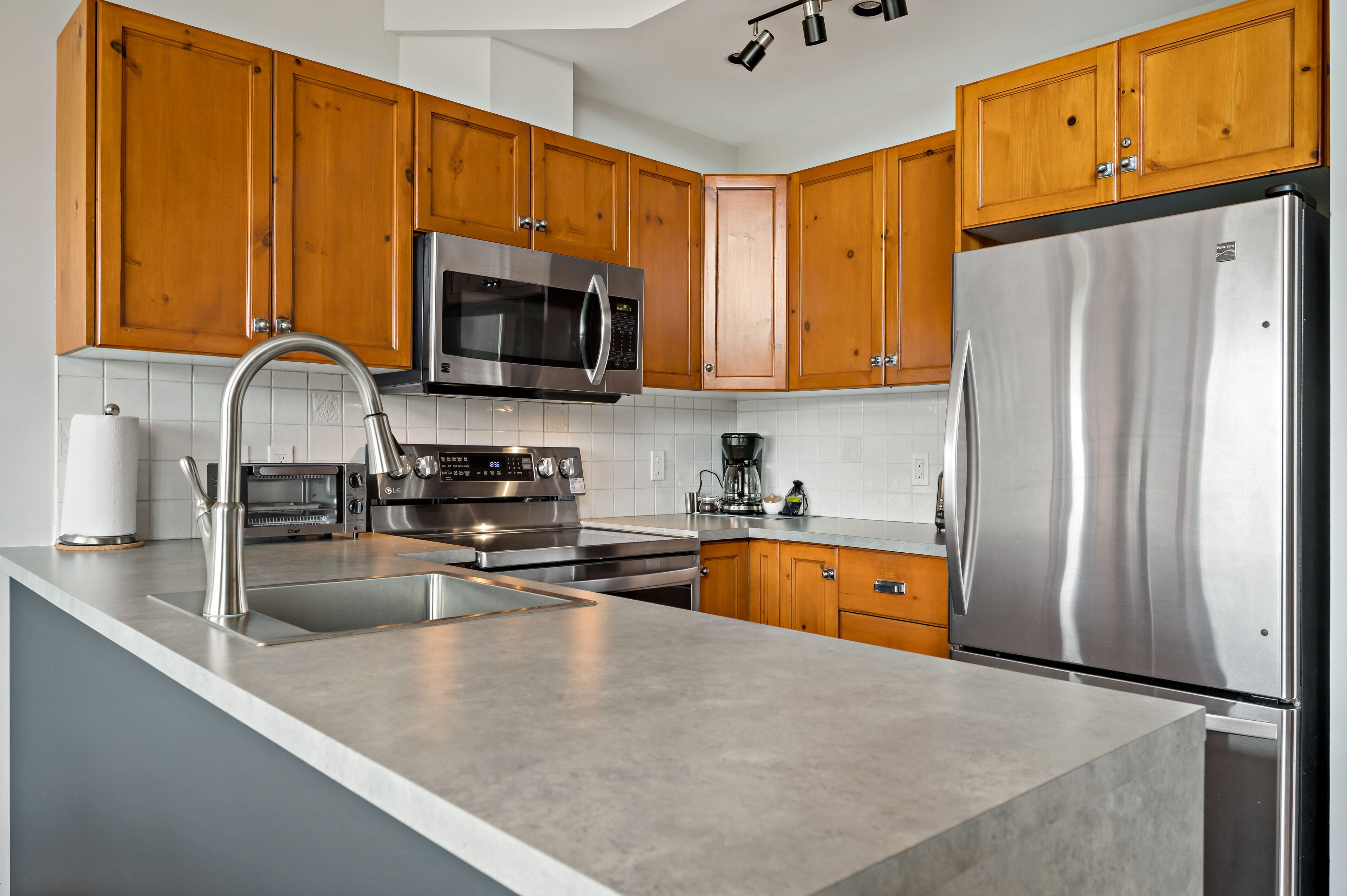 A modern kitchen with wooden cabinets, stainless steel appliances, and a large island with a sink.