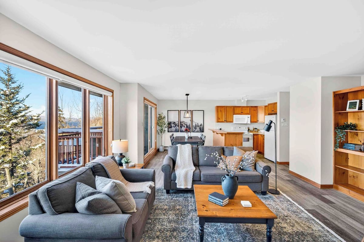 A modern living room with a sofa, coffee table, and a view of the kitchen.