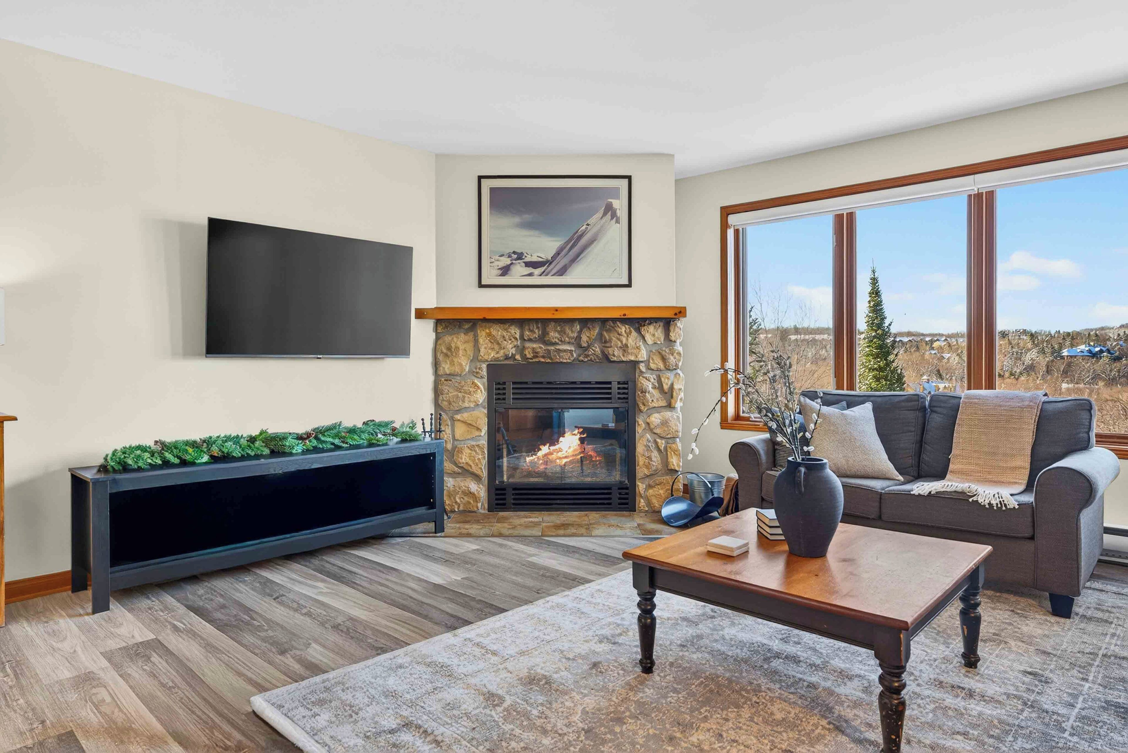 Una sala de estar con chimenea de piedra, televisor de pantalla plana, sofá y mesa de centro.