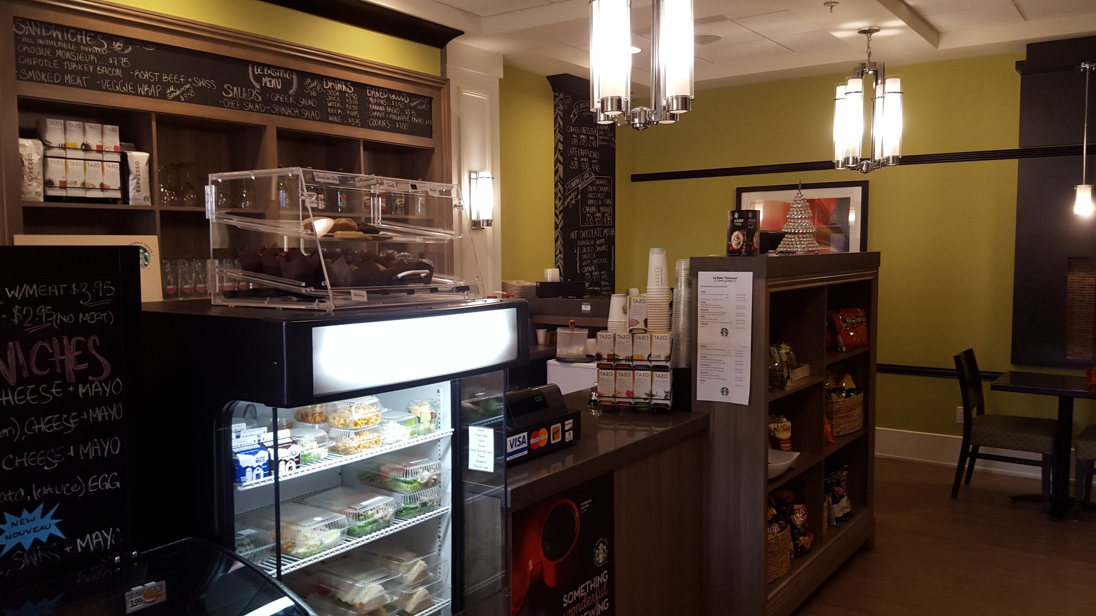 A cafe with a chalkboard menu, a self-serve beverage station, and a variety of snacks and condiments.