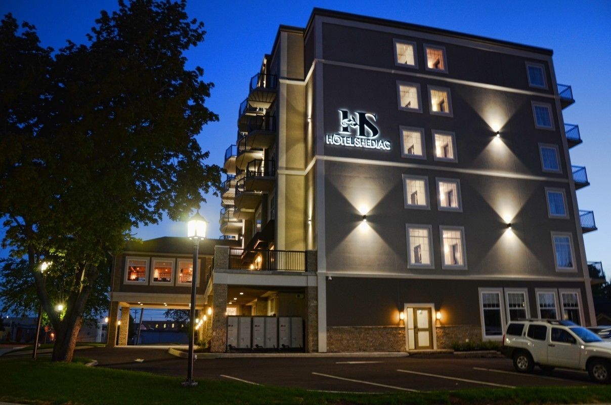 Un hotel de varios pisos con un diseño moderno, que cuenta con balcones y una entrada bien iluminada.