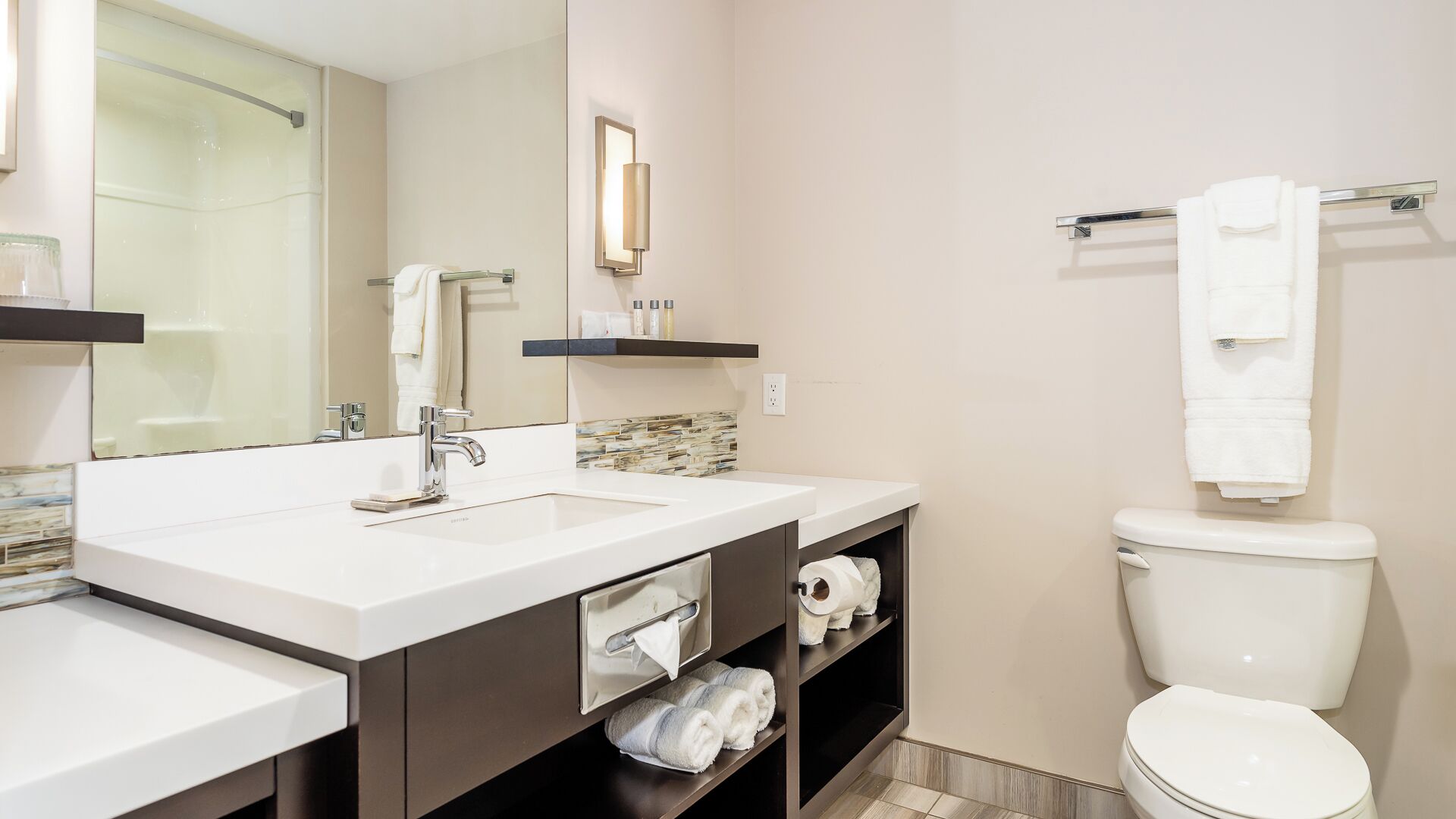 Un baño moderno con un lavamanos blanco, un espejo, un perchero para toallas y un inodoro.