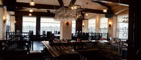 A bar area with multiple seating options, a bar counter, and hanging light fixtures.