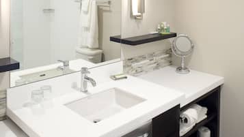 A modern bathroom with two sinks, a large mirror, and a towel rack.