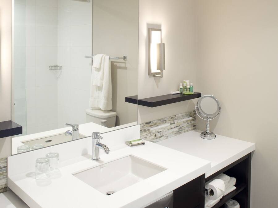 A modern bathroom with two sinks, a large mirror, and a towel rack.
