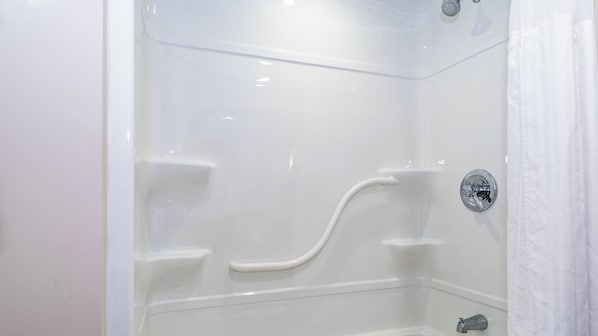 A white, modern shower with a curved handle and a chrome faucet.