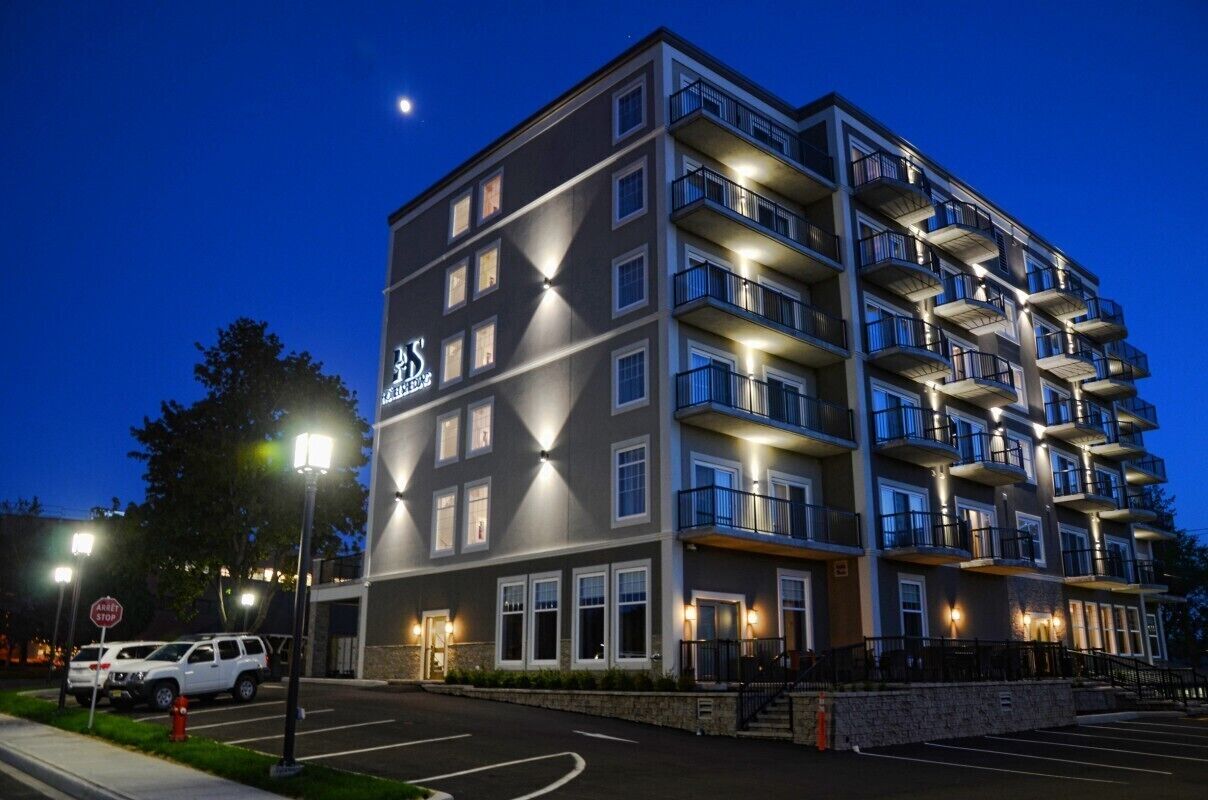 A multi-story hotel with a modern design, featuring balconies on each floor and a prominent sign on the building.