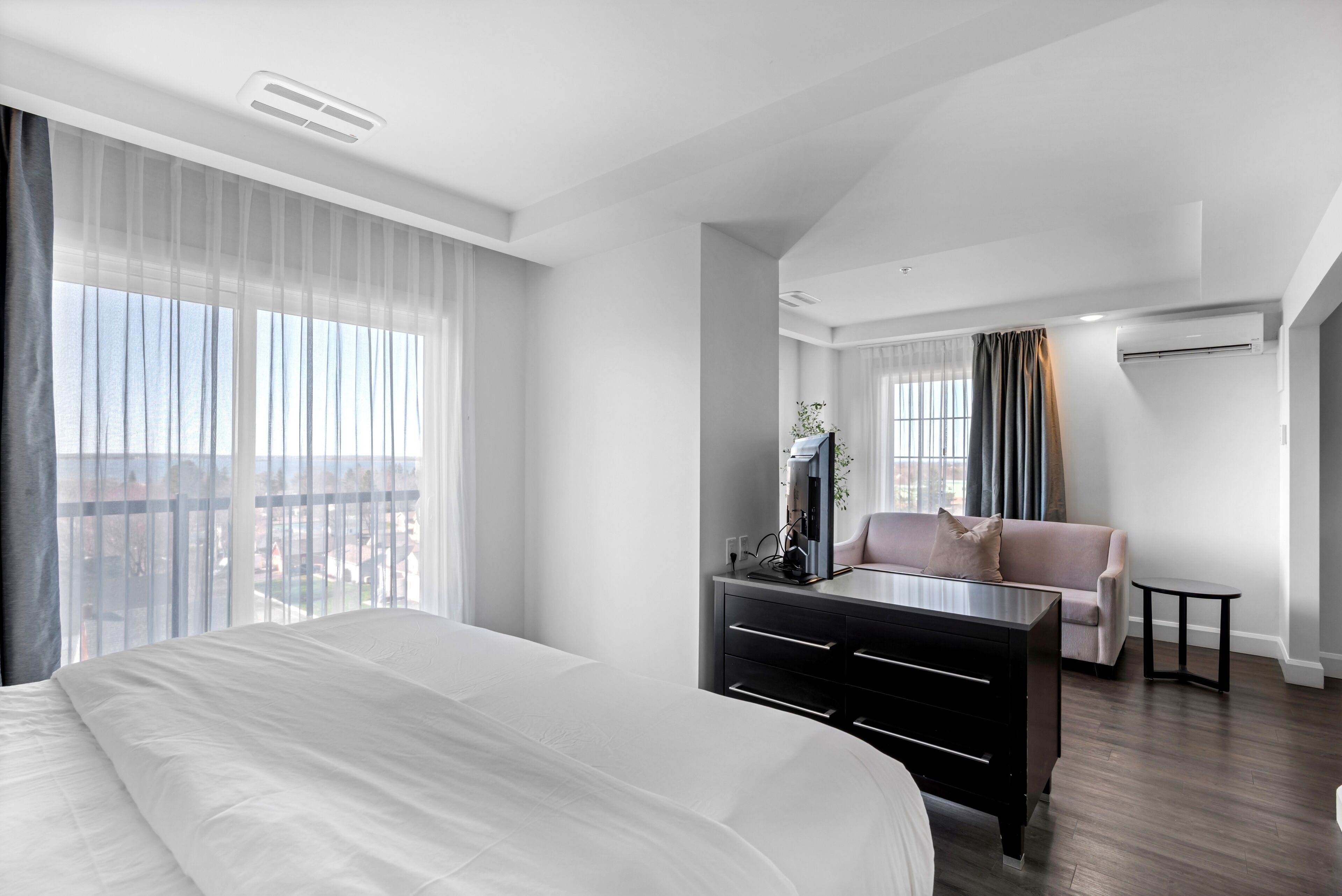 Quarto de hotel moderno com cama grande, escrivaninha, cadeira e varanda com vista.