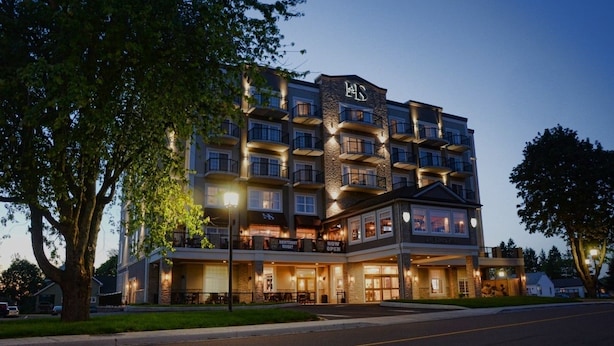Un hôtel à plusieurs étages, doté d’une façade en pierre, de nombreux balcons et d’une entrée bien éclairée.