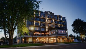 Un hôtel à plusieurs étages, doté d’une façade en pierre, de nombreux balcons et d’une entrée bien éclairée.