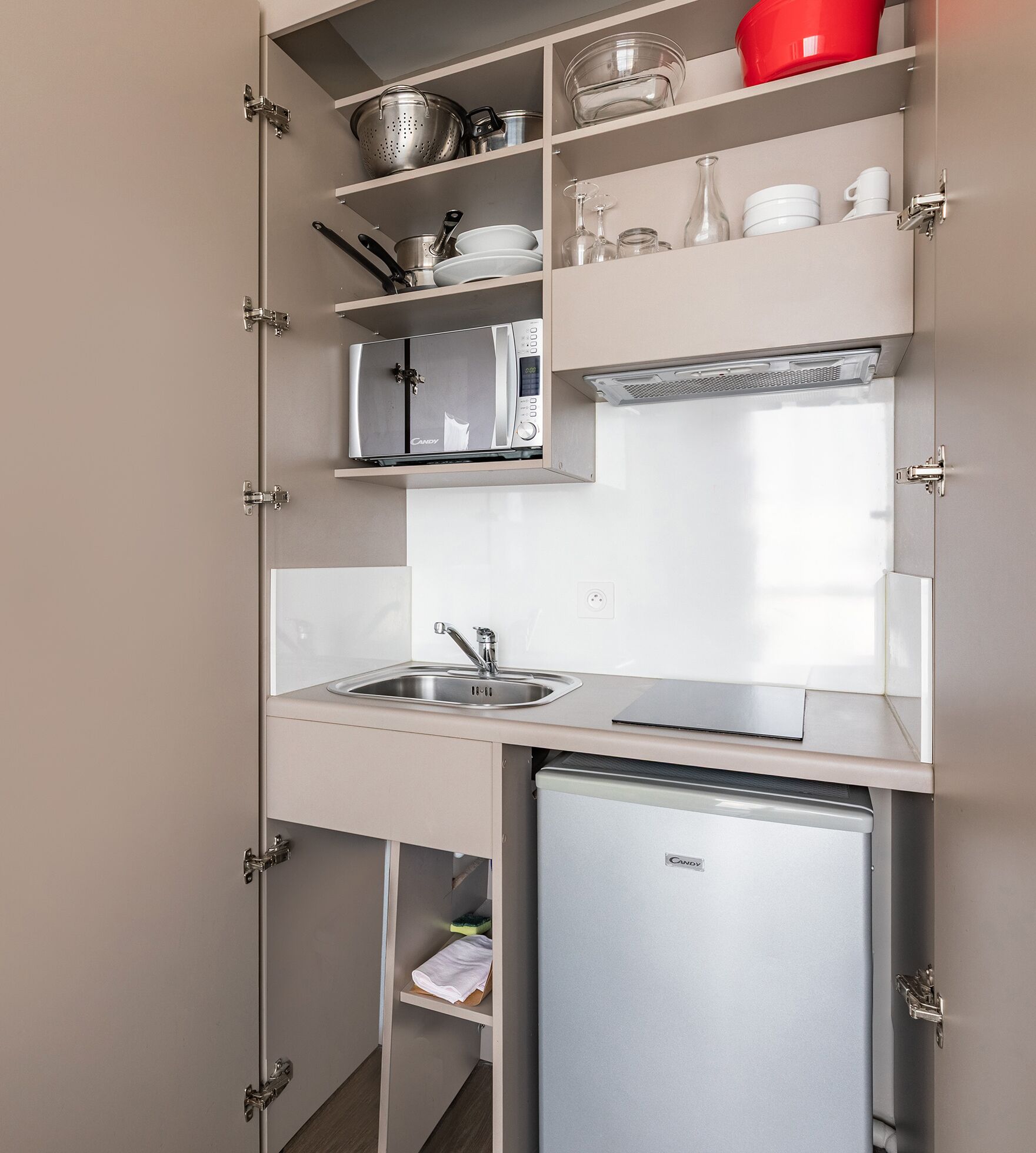A compact kitchen with a built-in microwave, a sink, and a small refrigerator.