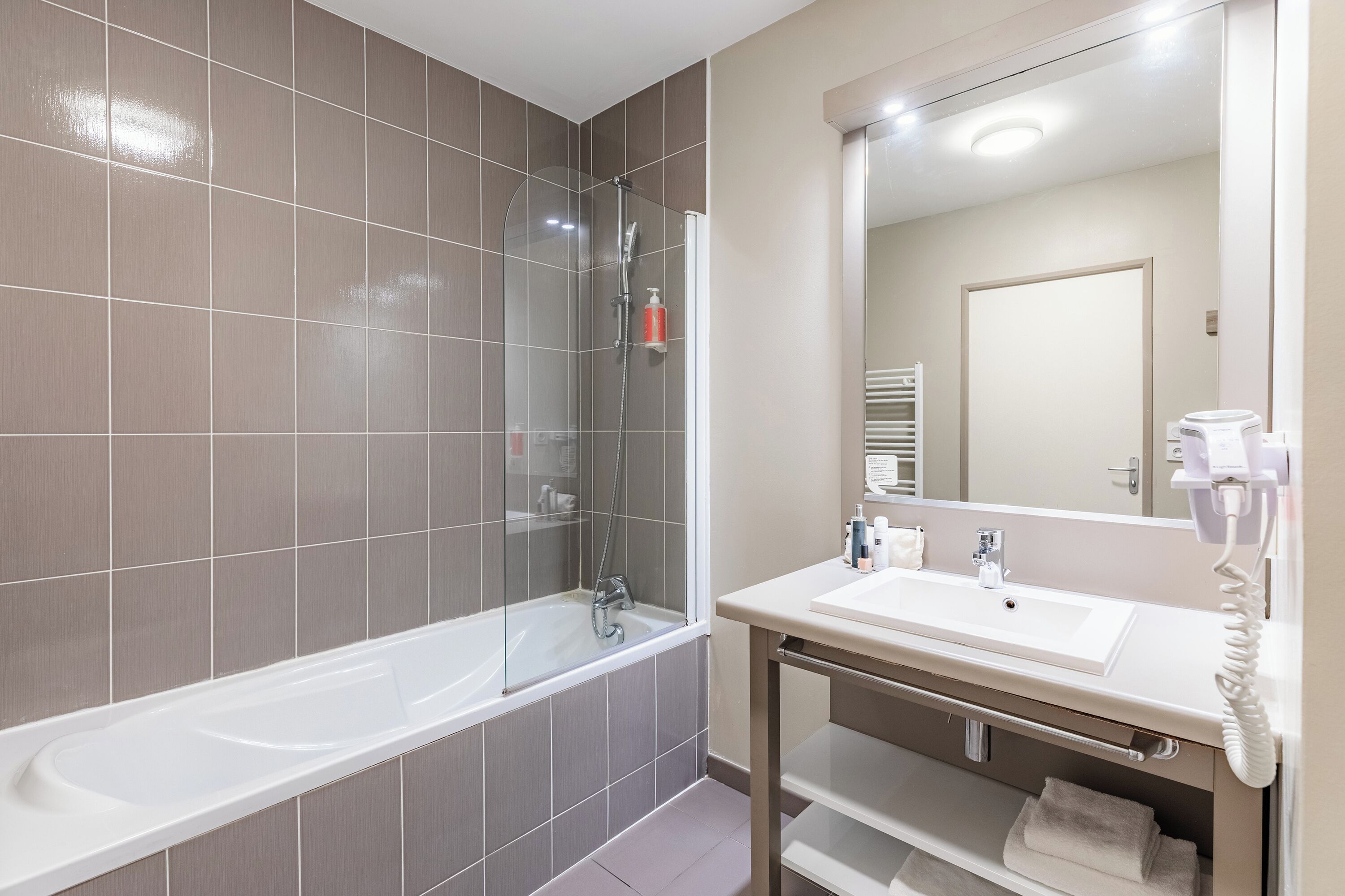 Une salle de bain moderne avec une baignoire, un lavabo et un miroir.