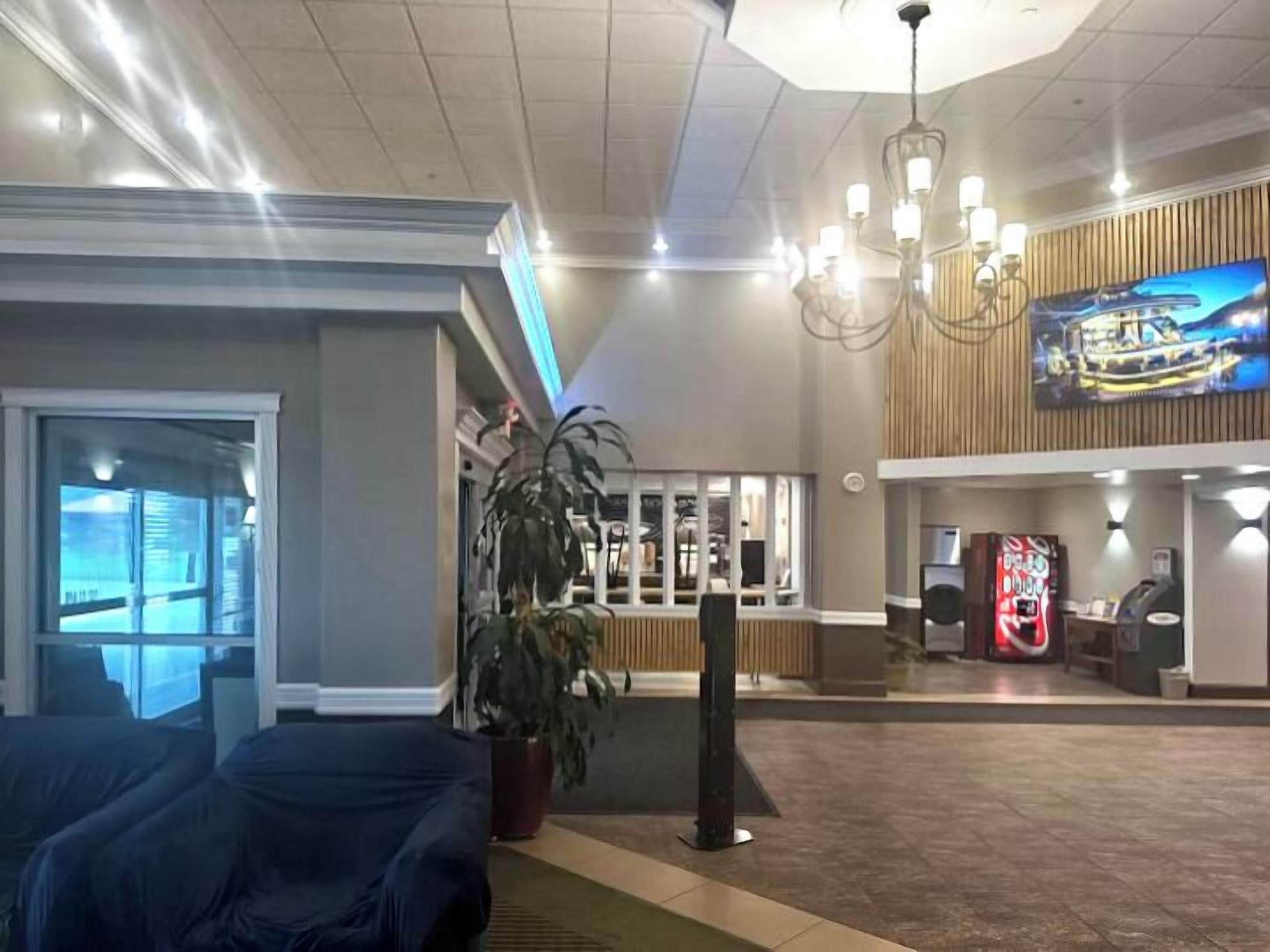 A lobby with a reception desk, a large TV screen, and a seating area with a potted plant.