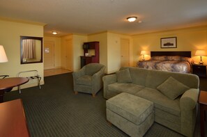Relax in comfort with a sofa set, armchairs, and a bed, plus a TV and a door to a separate room.