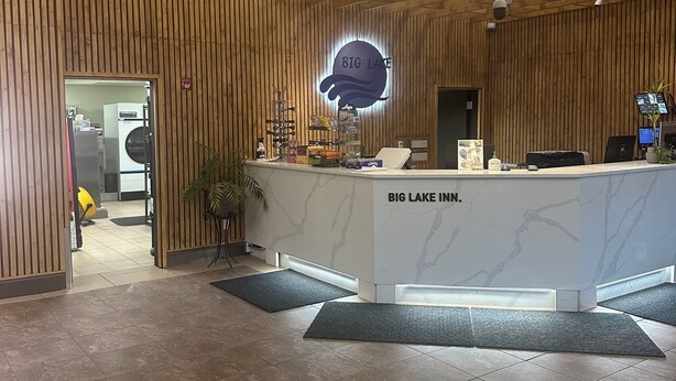 A reception area with a wooden panel wall, a marble counter, and a sign that reads "BIG LAKE INN." - Big Lake Inn (Slave Lake)