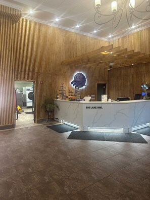 A reception area with a wooden panel wall, a marble counter, and a sign that reads "BIG LAKE INN." - Big Lake Inn (Slave Lake)