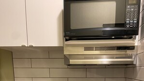 A kitchen with a stainless steel sink, a black countertop, a built-in microwave, and white cabinets. - Big Lake Inn (Slave Lake)