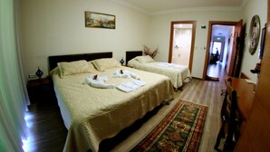 Ein Hotelzimmer mit zwei Betten, einem Bild an der Wand, einem Gang zu einem anderen Zimmer und einem Spiegel.