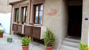 Ein Gebäude mit einem Schild mit dem Schriftzug 'Selena', Fenstern mit Fensterläden und Blumentöpfen.