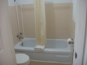Un baño con bañera, inodoro y cortina de ducha.