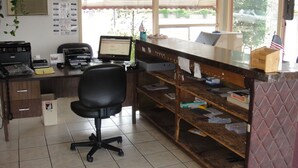 Una oficina pequeña con escritorio, computadora, impresora y una silla.