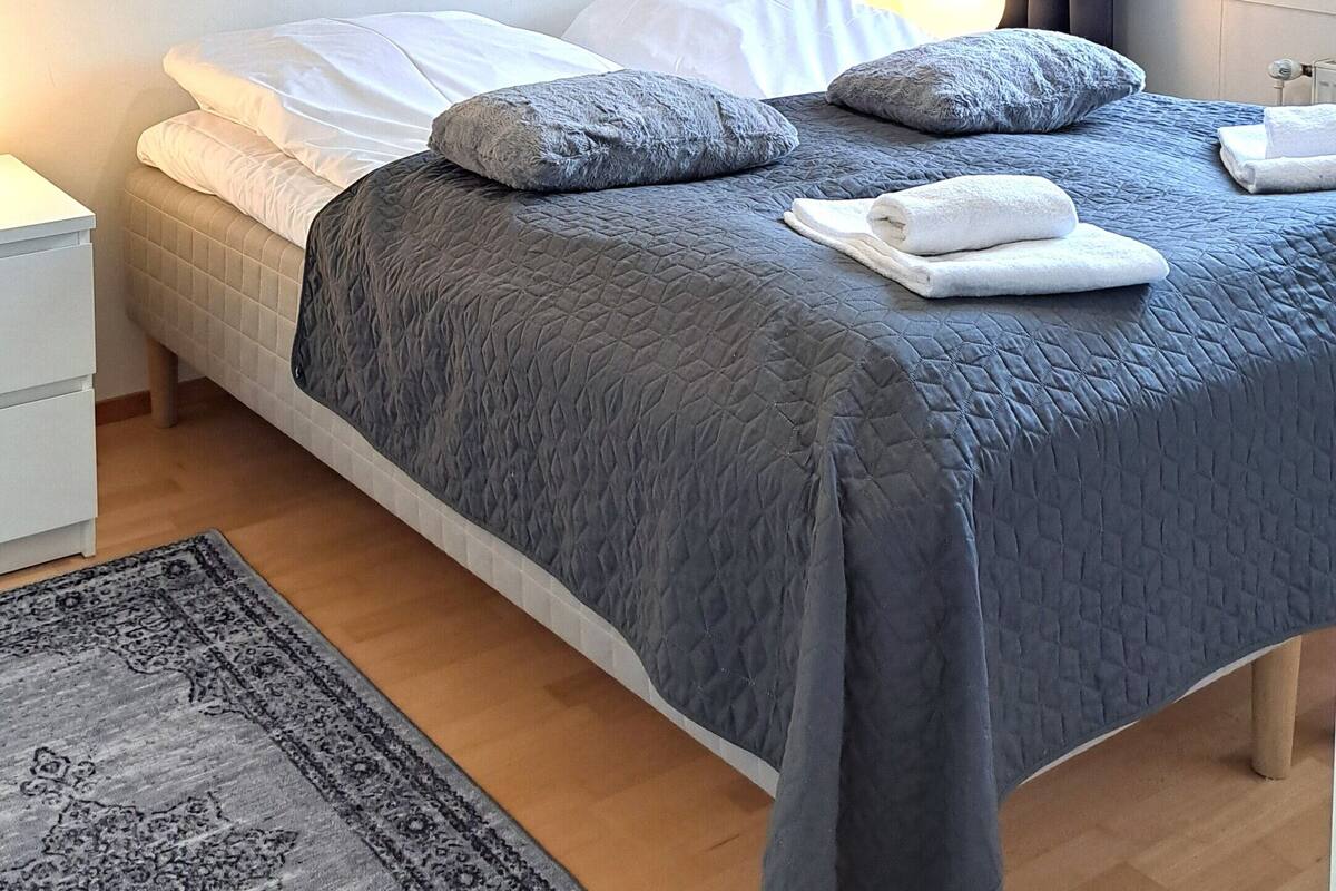 Une chambre à coucher avec un lit, des tables de chevet, un tapis et une fenêtre avec des rideaux.