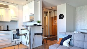 Un appartement moderne comprenant un coin cuisine, un espace repas, un salon avec un canapé et une salle de bain dotée d’une porte en verre.