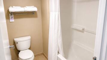 A bathroom with a toilet, a shower with a glass door, and a towel rack with folded towels.