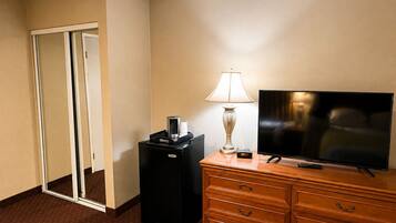 A hotel room with a flat-screen TV, a lamp, a coffee maker, and a dresser.